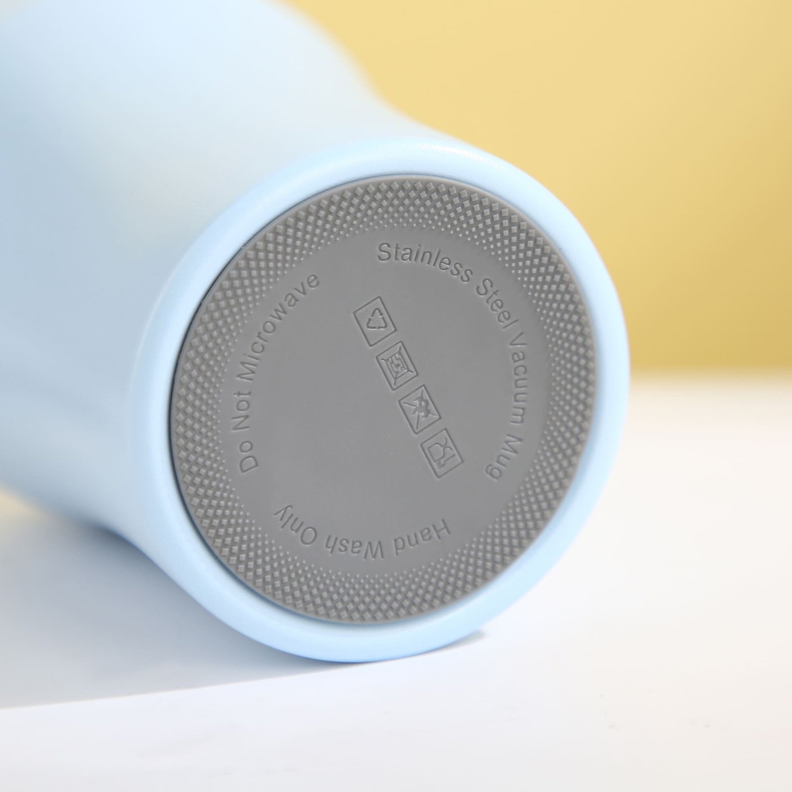 Detailed close-up of the integrated non-slip gray silicone base pad on an insulated travel mug showing regulatory symbols.