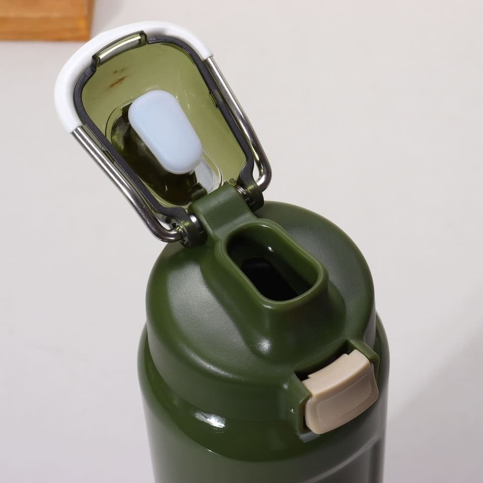 Open view of a green athletic water bottle cap showing the drinking spout and internal white silicone sealing plunger block.