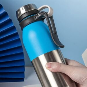 Overheard view of a vibrant blue 550ml tactical handle vacuum bottle with a rugged black tactical finger-groove handle being held against a marble background.