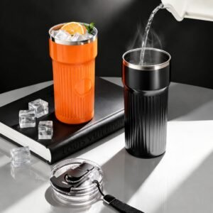 Orange and black 600ml ribbed vacuum insulated tumbler with ice cubes and hot water pouring